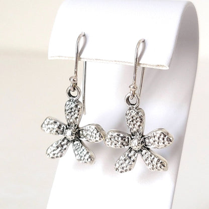 Sterling silver flower dangle earrings, shown on a display stand.