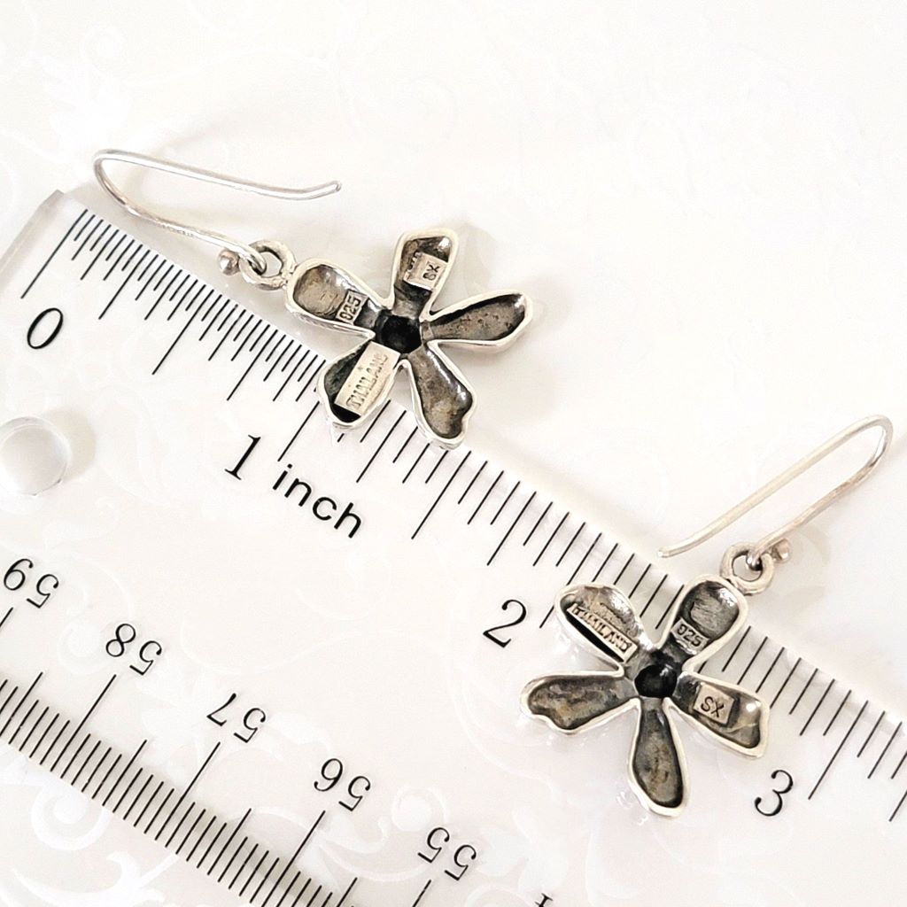 Sterling silver flower earrings, next to a ruler.