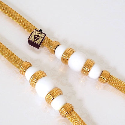 Closeup view of white beads on a vintage Anne Klein gold tone mesh tube style necklace.  Also has a paper lion logo tag.