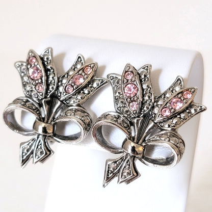 Vintage rhinestone Avon pink tulip clip earrings, shown on a display stand. Silver tone, faux marcasite, bow tied, bouquet style.