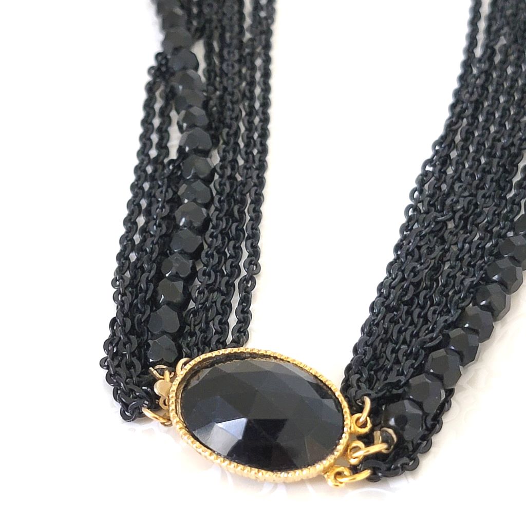 Closeup view of a box clasp on a black multistrand necklace.