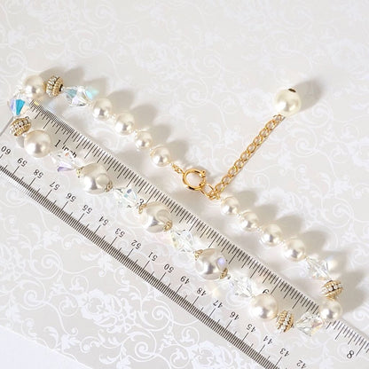 Vintage faux pearl and glass choker, with gold tone accents and extender chain, shown next to a ruler.