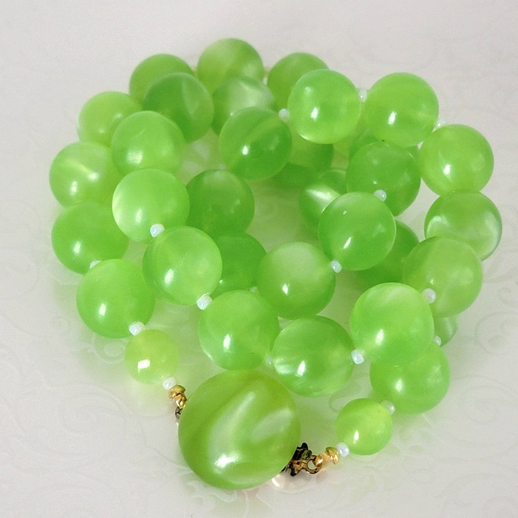 Closeup of vintage bright green beaded moonglow necklace, with matching clasp.
