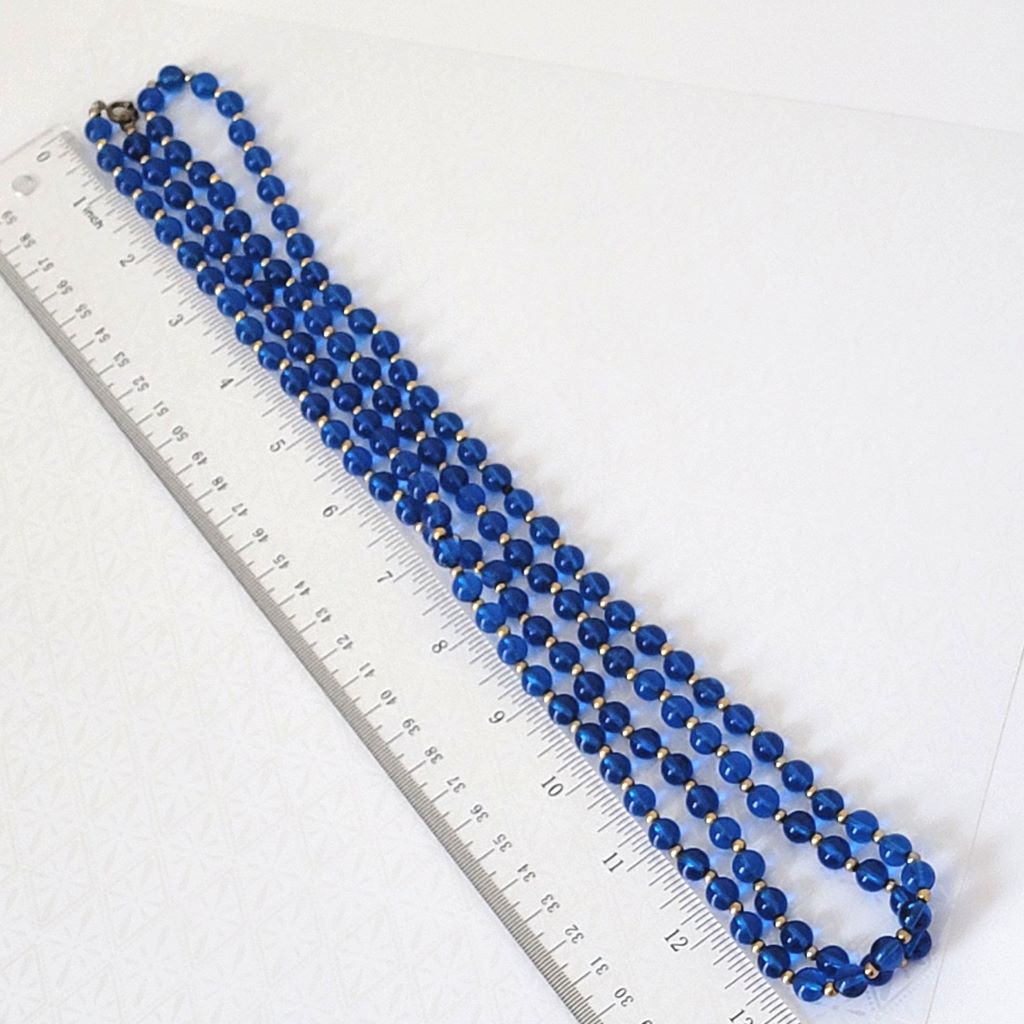 Vintage translucent blue plastic beaded, long 60s necklace, shown next to a ruler.