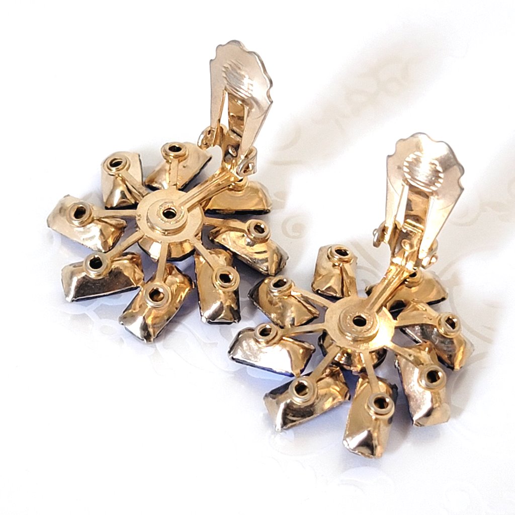 Back view of a pair of clip on earrings, showing gold tone riveted construction and prong baguette settings.