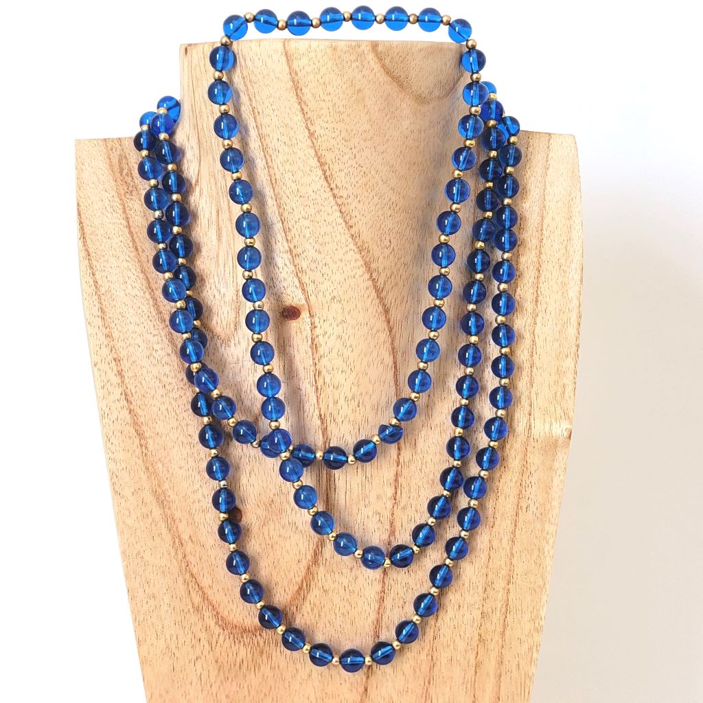 Vintage translucent blue plastic beaded, long 60s necklace, on display stand.