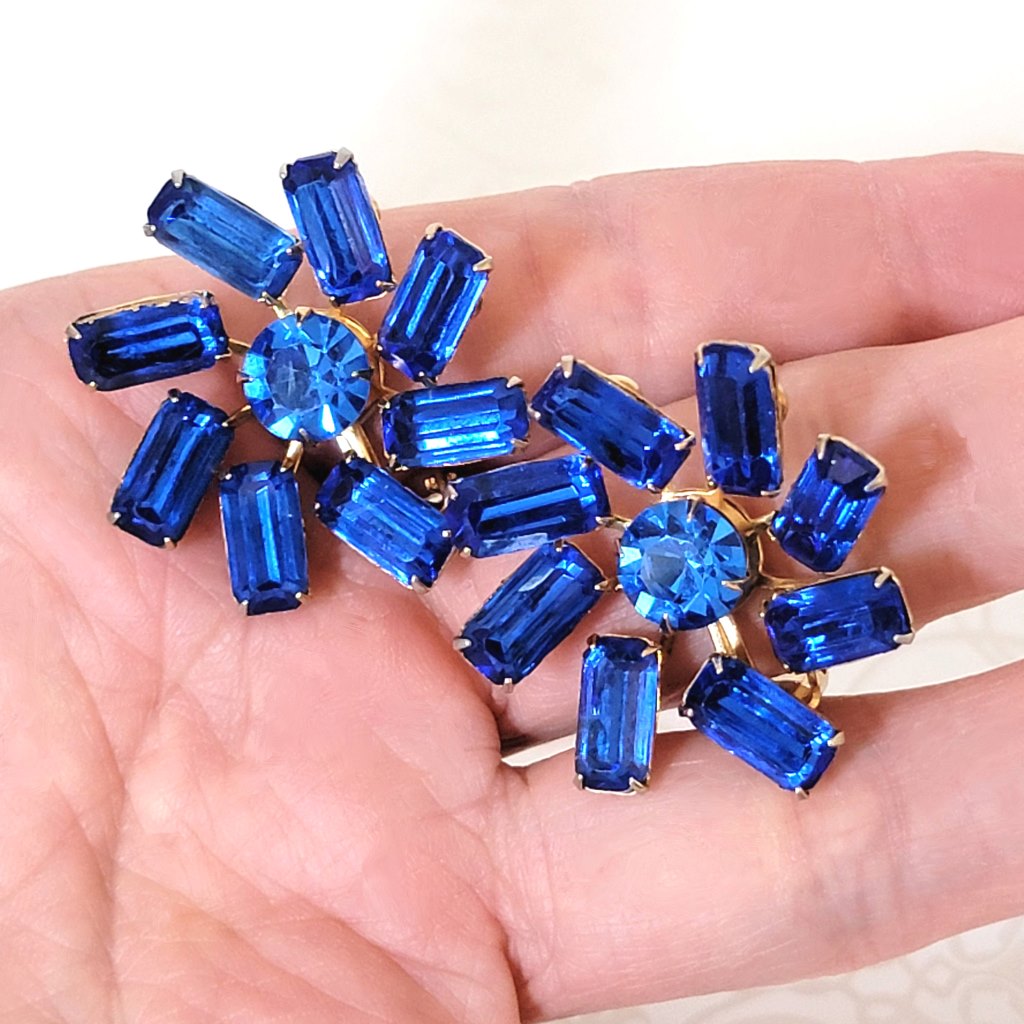 Vintage sapphire blue, baguette rhinestone clip on earrings, with a fan-like prong setting. Shown in hand, for size comparison.
