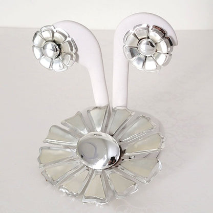 Vintage silver tone 60s flower brooch and earrings set, shown on a display stand.