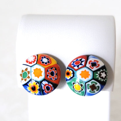 Vintage button style millefiori floral multicolor glass clip-on earrings. Shown on a  display stand.