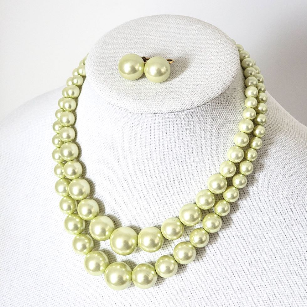 Vintage two strand light yellow faux pearl choker necklace and matching clip on earrings, shown on a display stand.